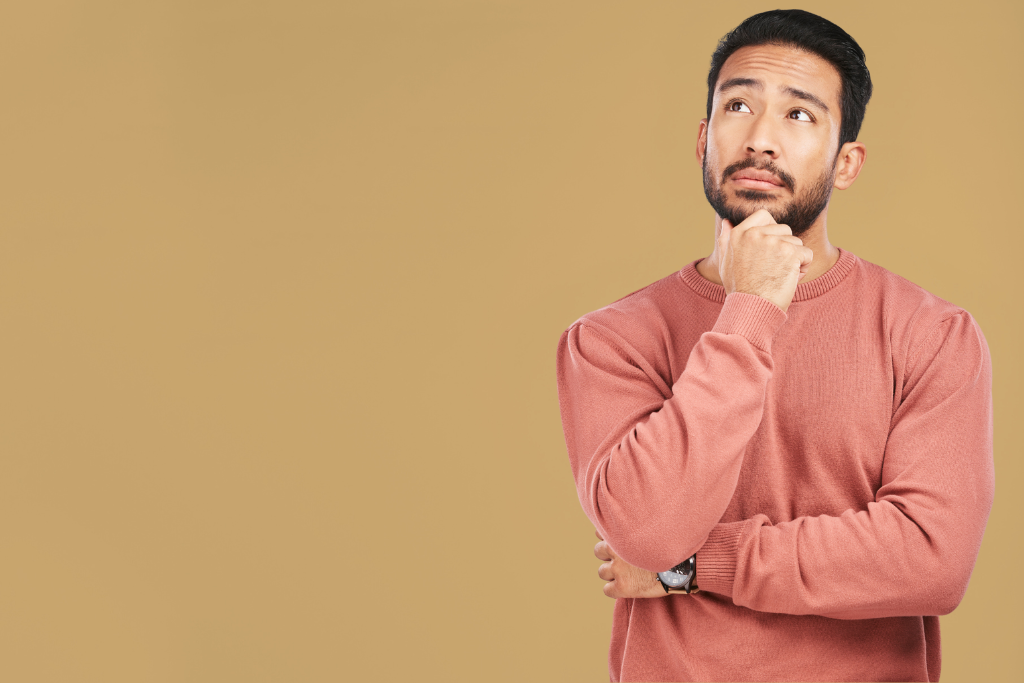 Young man stood up wearing pink cardigan pondering property FAQs